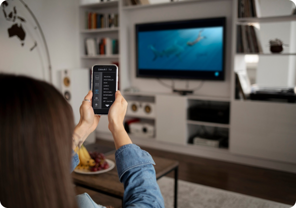A person with a cellphone pointing at a television