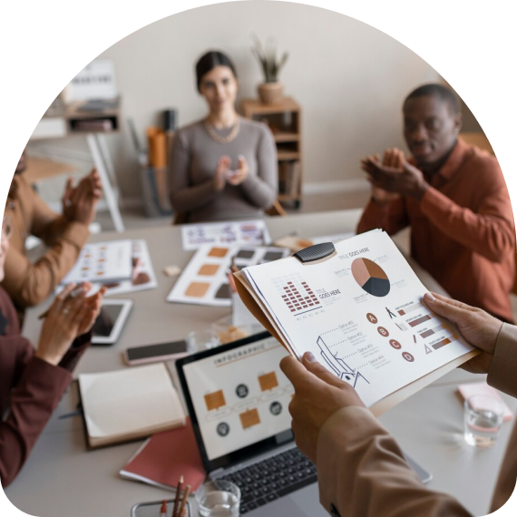 Four people working at a table full of papers with charts