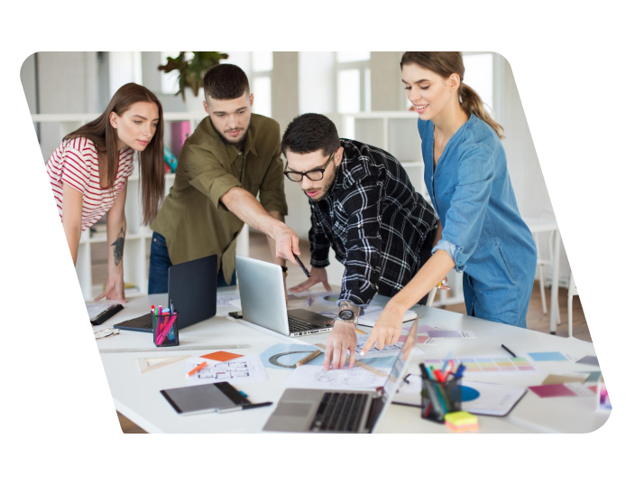 People looking at a table with papers and a computer