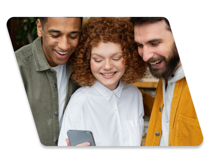 Three people looking at a cellphone and smiling
