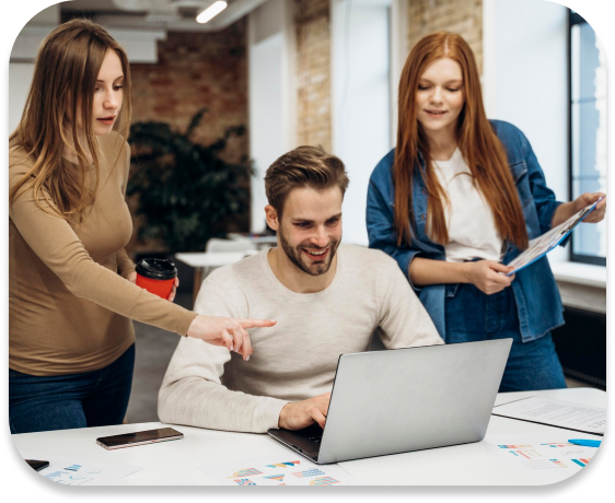 A person sitting with their laptop and two others standing, all looking at the same computer